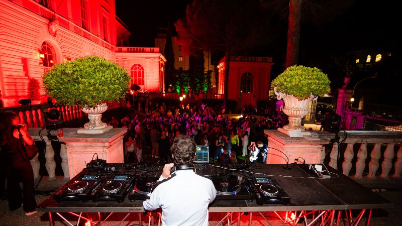 Color photo of a DJ and a dancing crowd