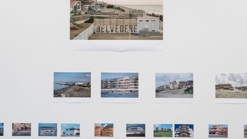 Color photograph of a gallery wall that displays color photos of Italian seascapes