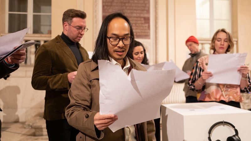 Color photograph of a group of people reading from pieces of paper with writing printed on them