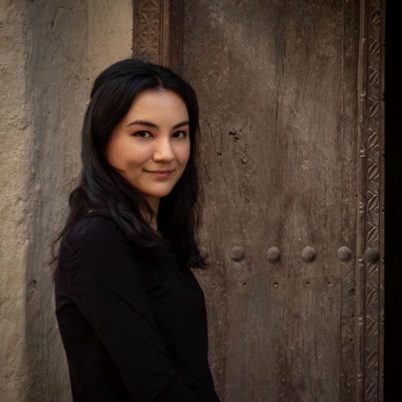 color photo of a 3/4 view of a dark haired light skinned woman smiling at the camera