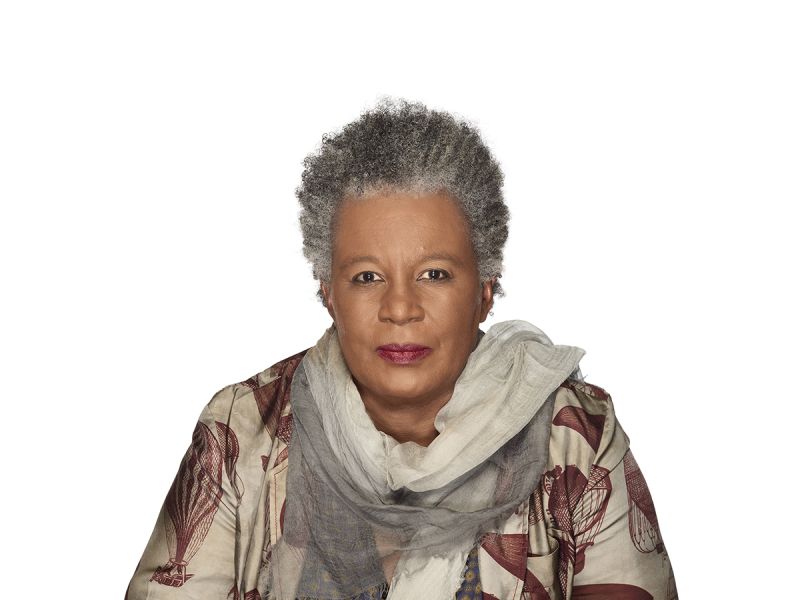Color photograph of a dark skinned woman with gray hair looking directly at the camera