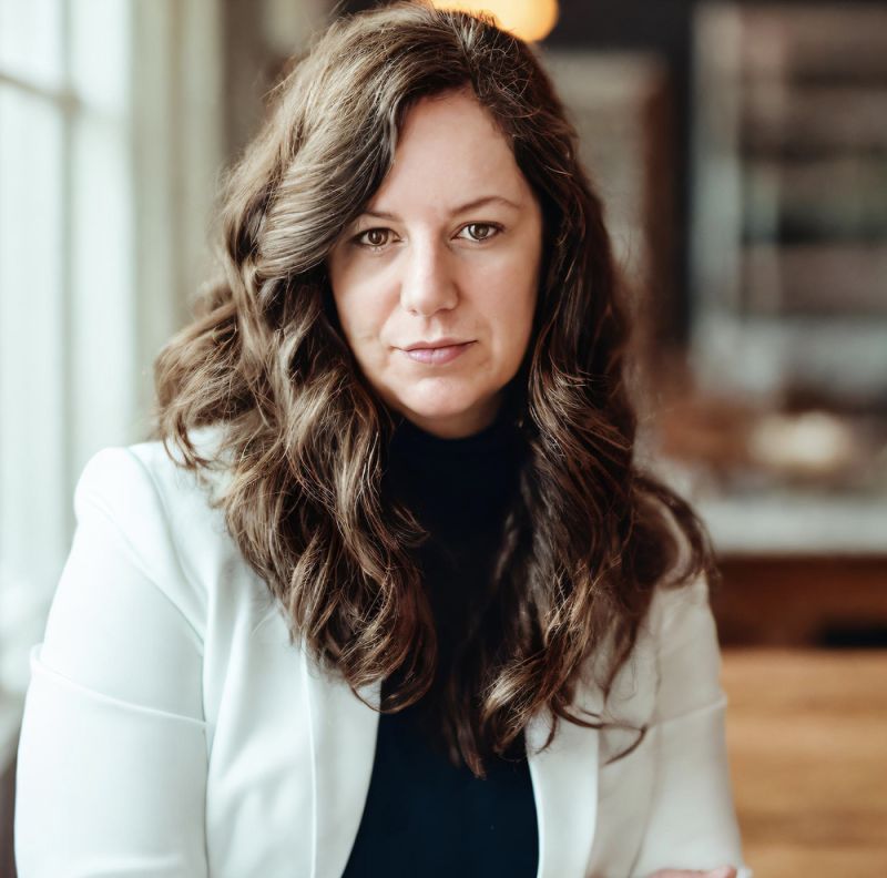 color photo of a woman with brown hair looking at the camera