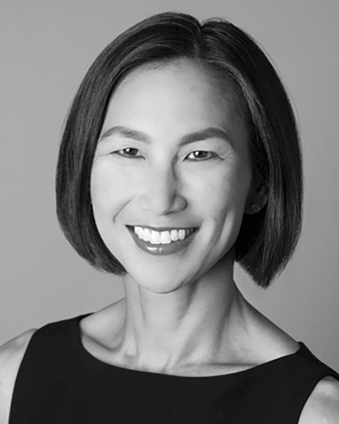 Black and white photo of the head of an Asian woman smiling at the camera