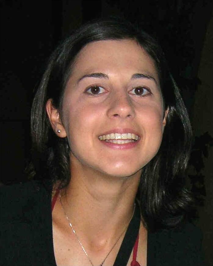 Color photo of the face and neck of a smiling light skinned woman with dark hair