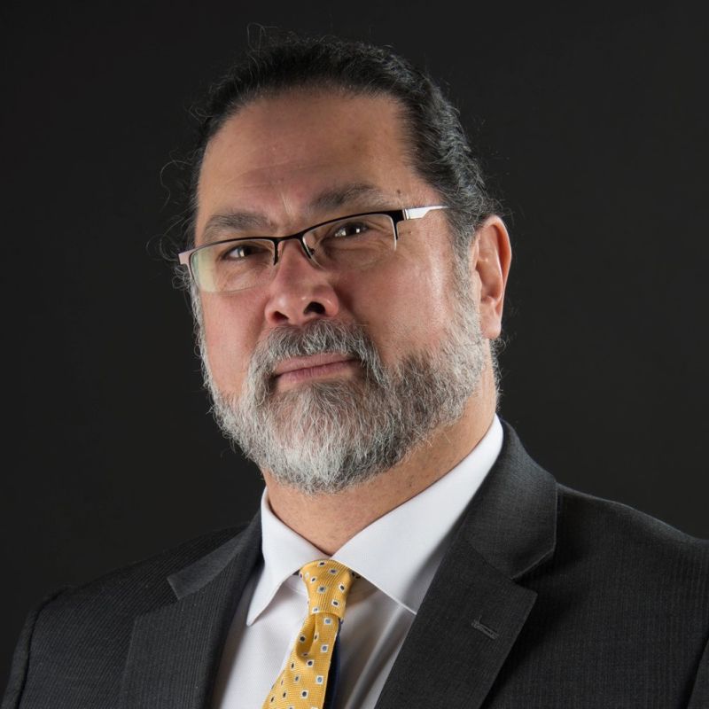 Color photograph of the head and shoulders of David Ogawa, wearing a suit and tie