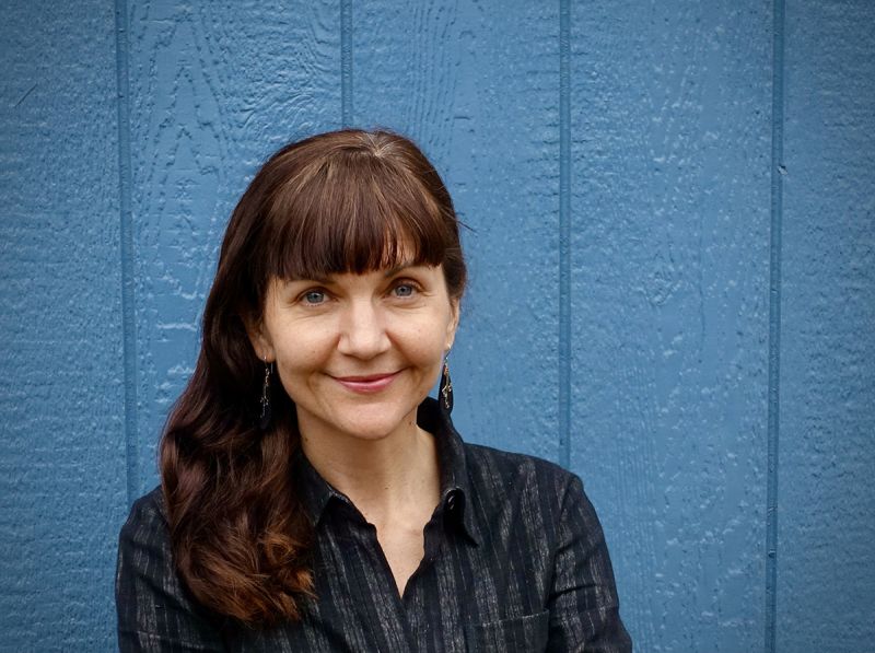 Color photograph of the head and shoulders of Elena Past standing against a blue wall