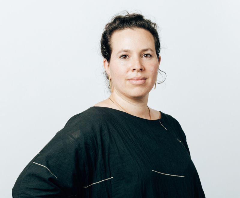 Color portrait of Katy Barkan, facing the camera and wearing a black dress with short, scattered white lines