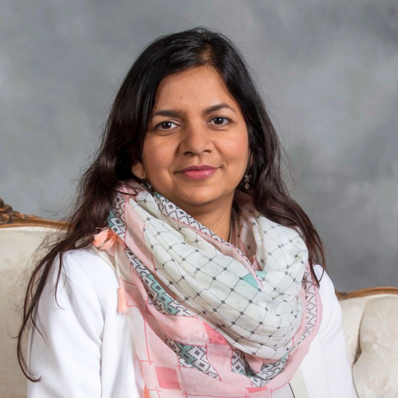 Color photo of an Indian woman in a photographer's studio smiling at the camera