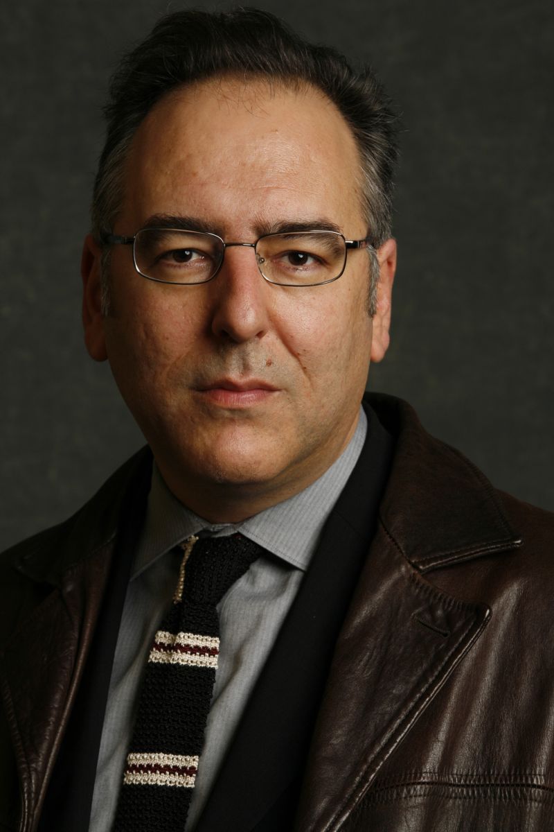 Color photograph of the head and shoulders of a light skinned man in a photographer's studio looking directly at the camera