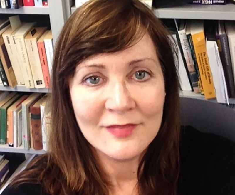 Color portrait of the head of Rebecca Messbarger, sitting in an office in front of a bookshelf
