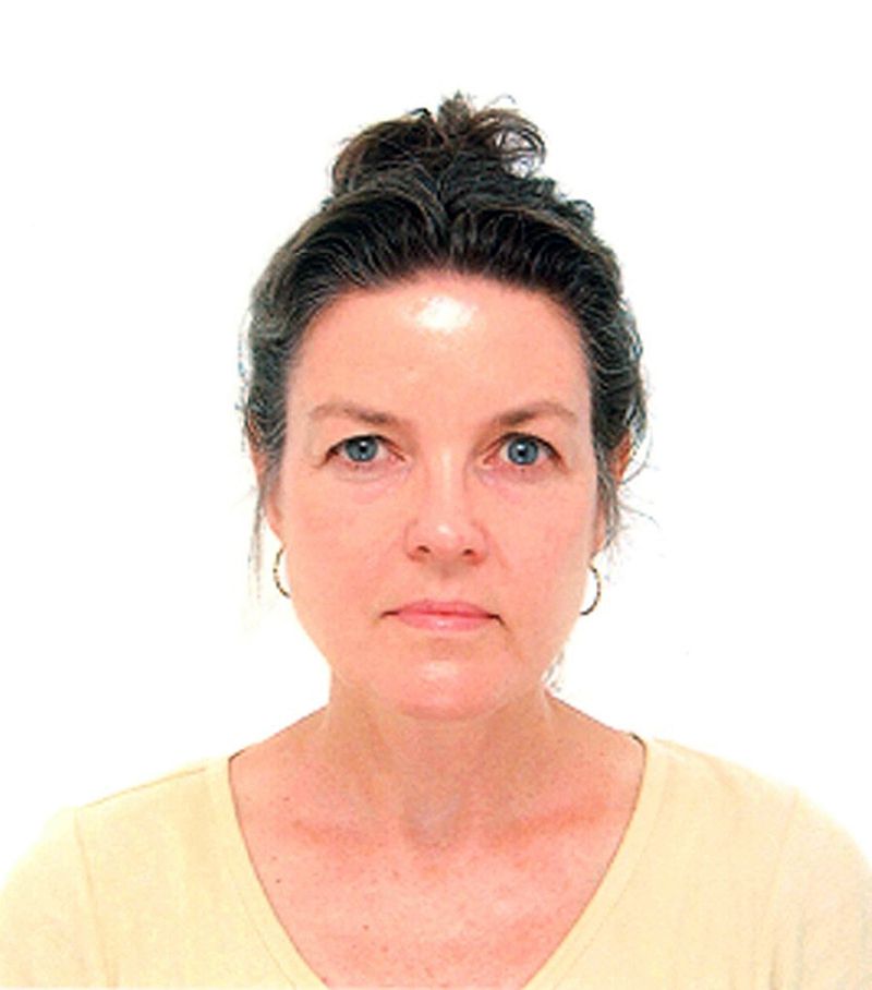 Color passport photograph of the head and shoulders of a light skinned woman wearing her brown hair in a bun