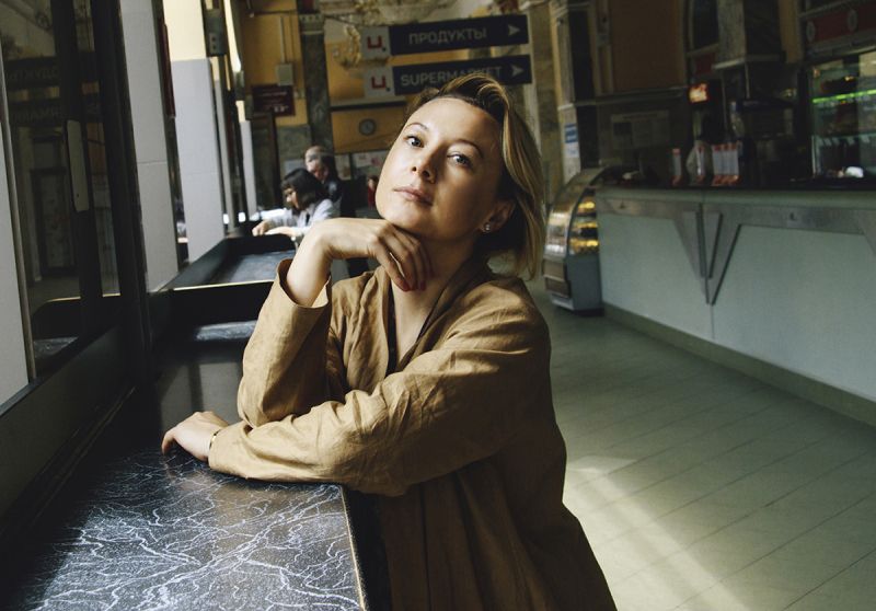 Color photograph of Valzhyna Mort standing at an eating counter inside a Belarusian delicatessan