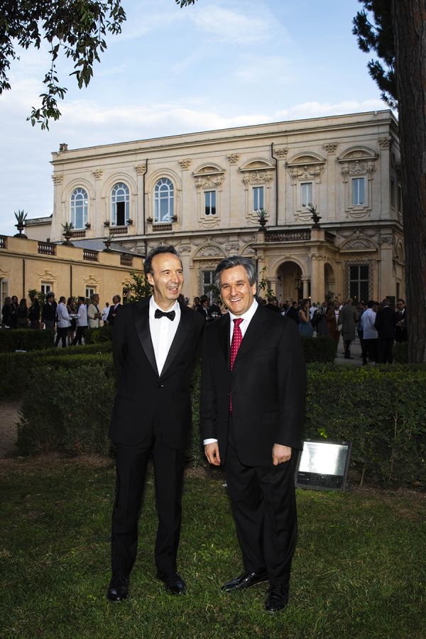 color photo of two men standing in front on villa